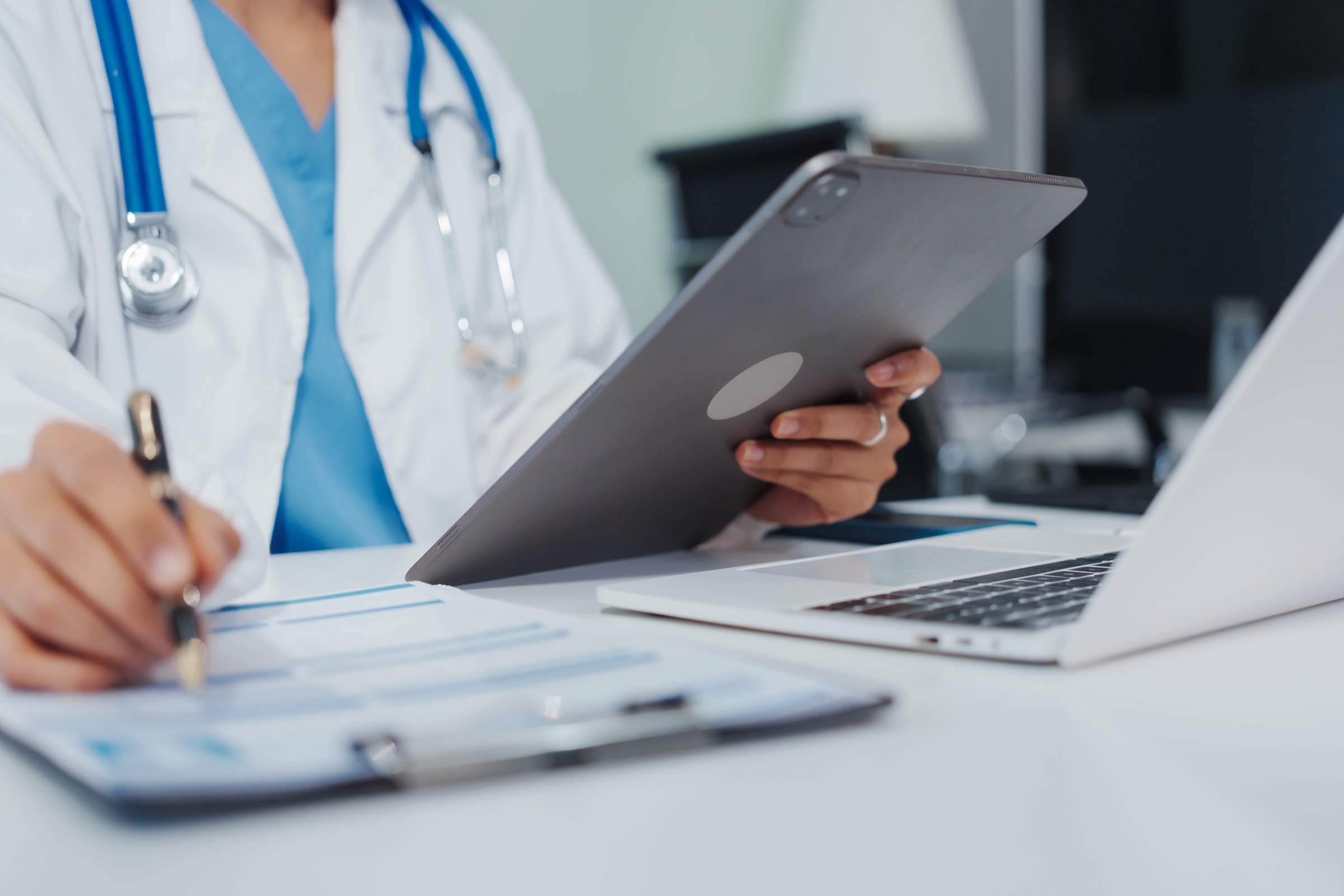 Asian female doctor is reviewing medical records, working on a computer, planning treatment, giving online consultations, and explaining medications to patients via a medical video call in a clinic