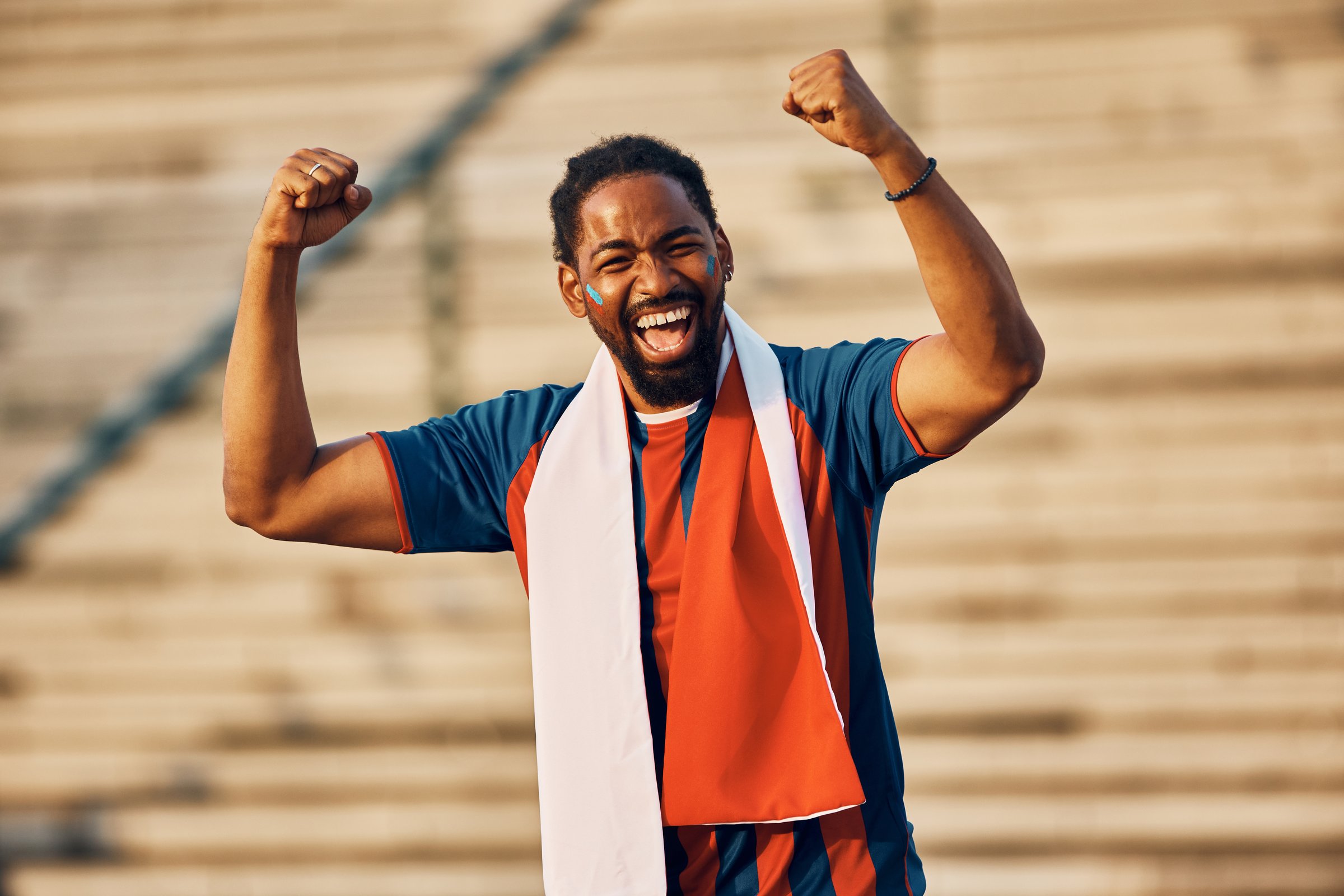 Cheerful African American soccer fan celebrating favorite team's victory and looking at camera.