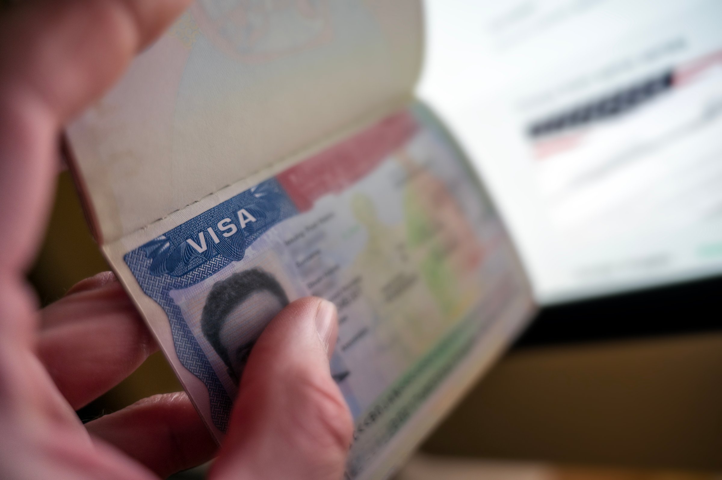 Unknown causian person holding passport with visa issued for United States of America