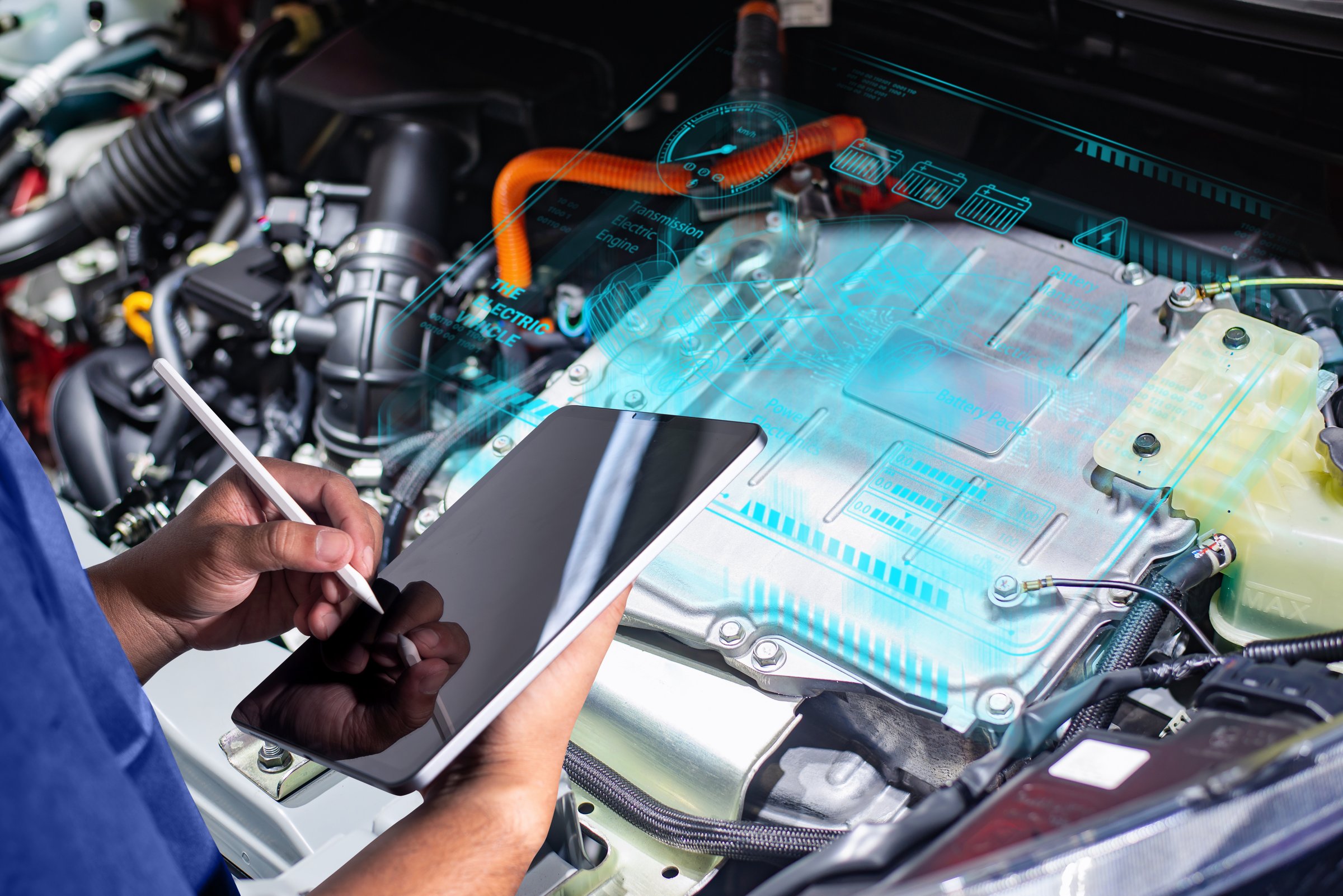 Technician using a tablet to analyze and diagnose an electric vehicle engine, showcasing modern automotive technology and diagnostics.