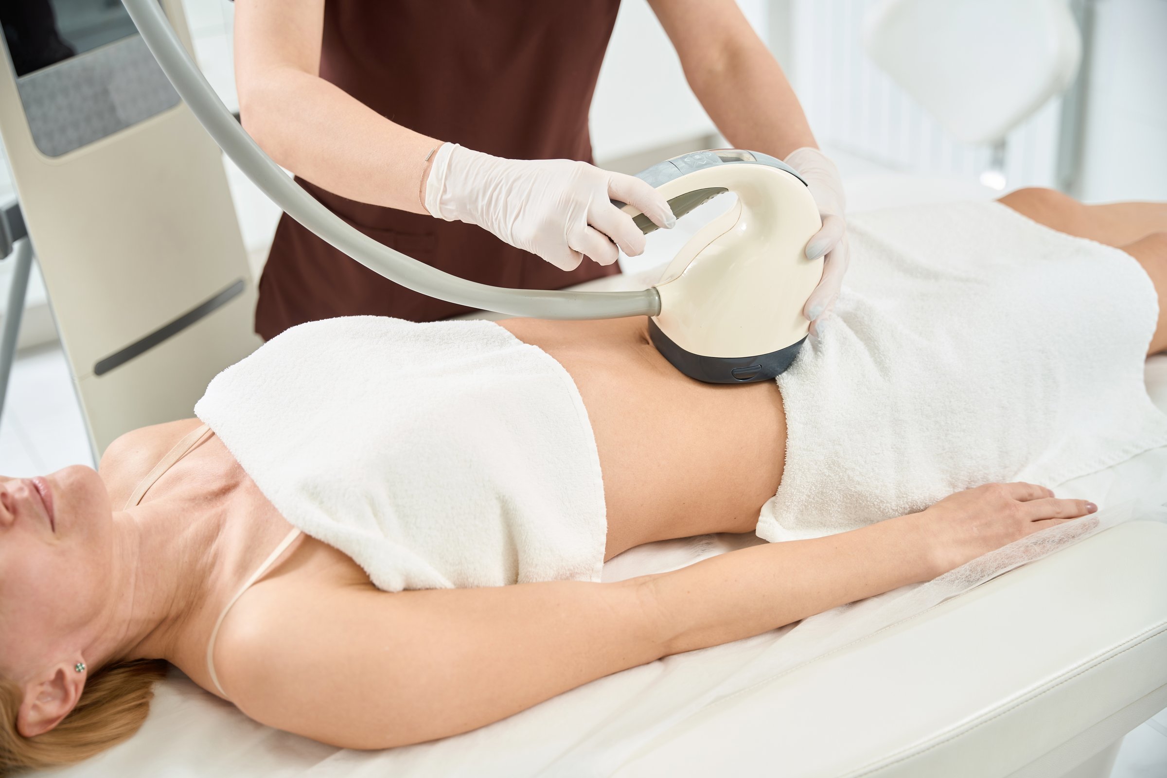 Woman attending cellulite reduction treatment with velashape apparatus that stimulating growth of new and better collagen and elastin which results in localized reduction in skin laxity, body volume