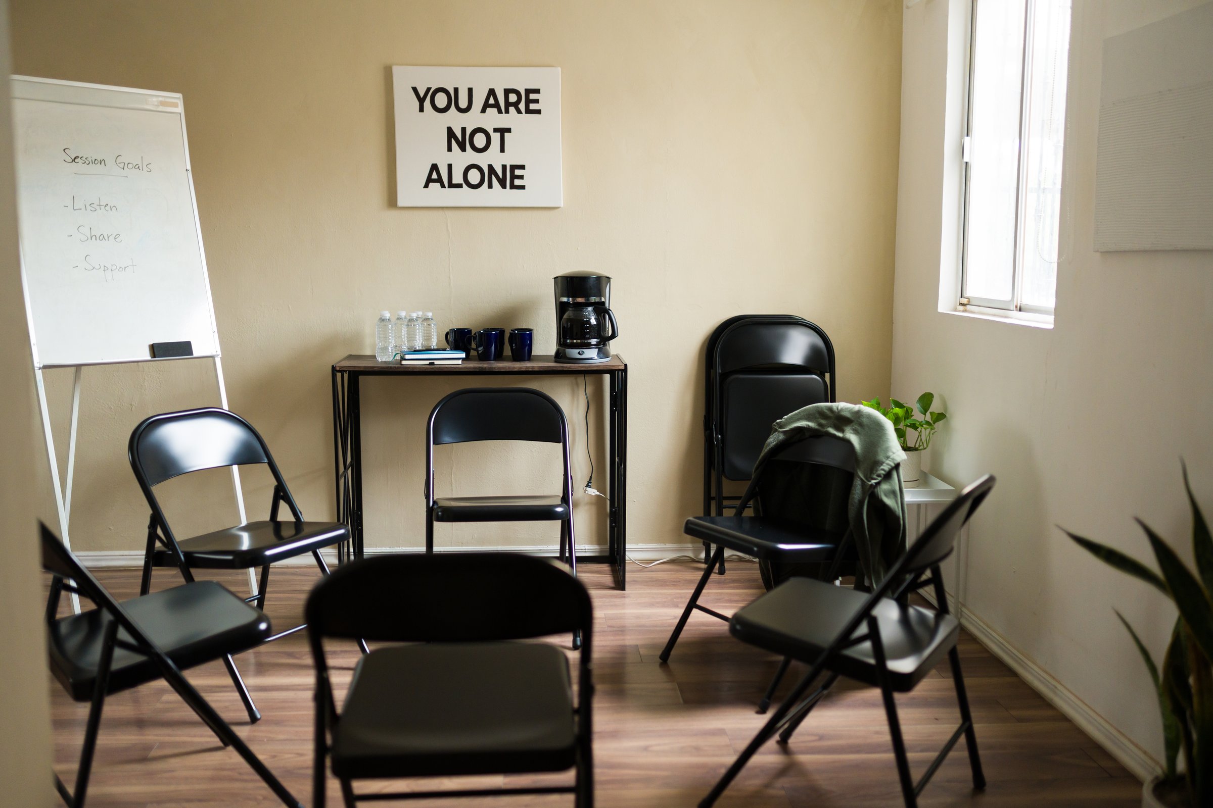 Empty chairs arranged in a circle for a peer support or therapy session, emphasizing mental health and community