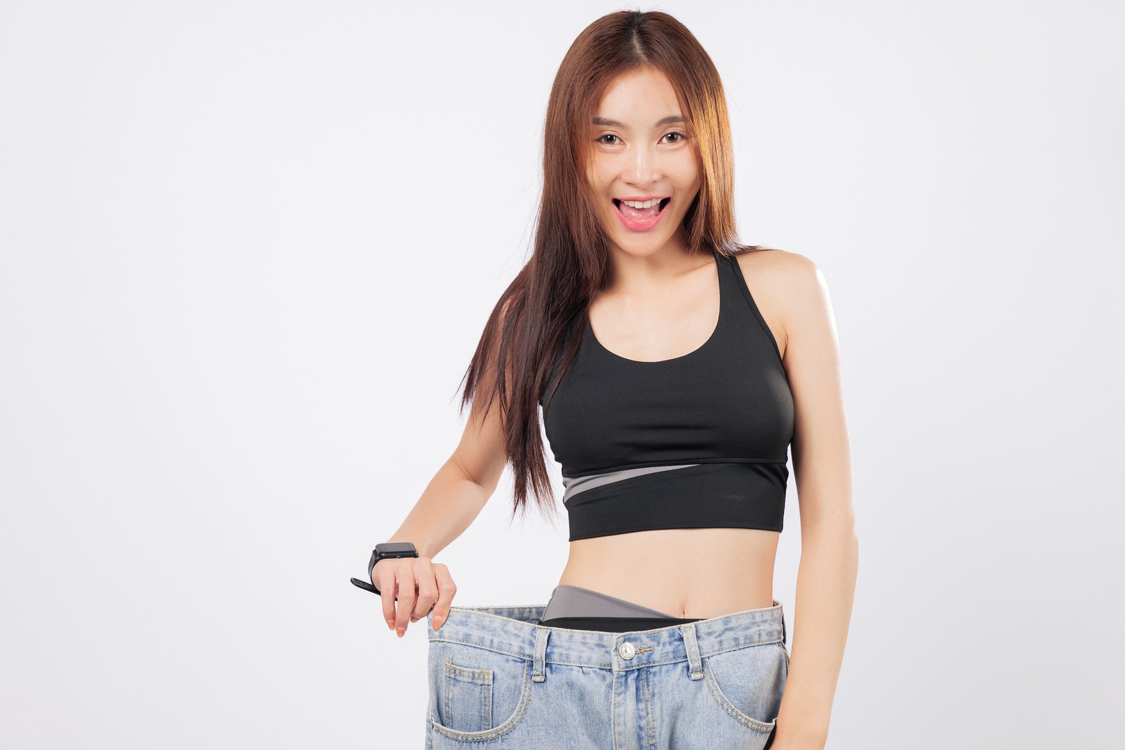 Weight loss success visible in her oversized pants and slim waist. She reflects on the journey and how weight struggles became her greatest motivation. isolated studio white background