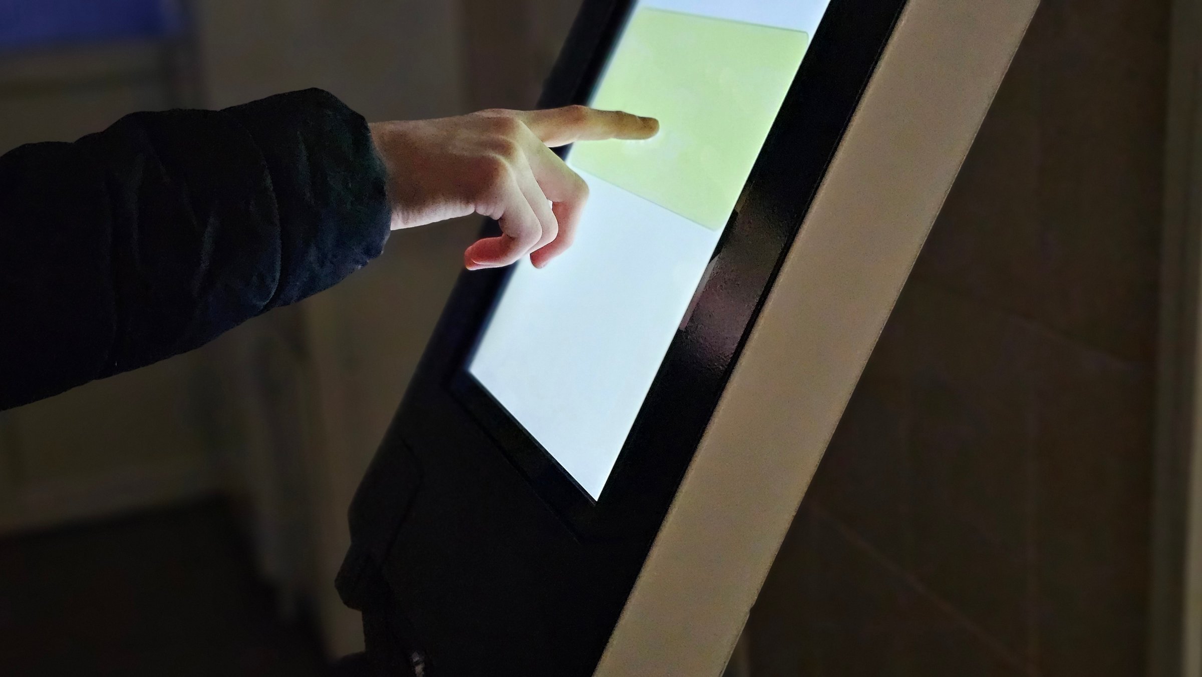 Teenager interacts with touch screen kiosk
