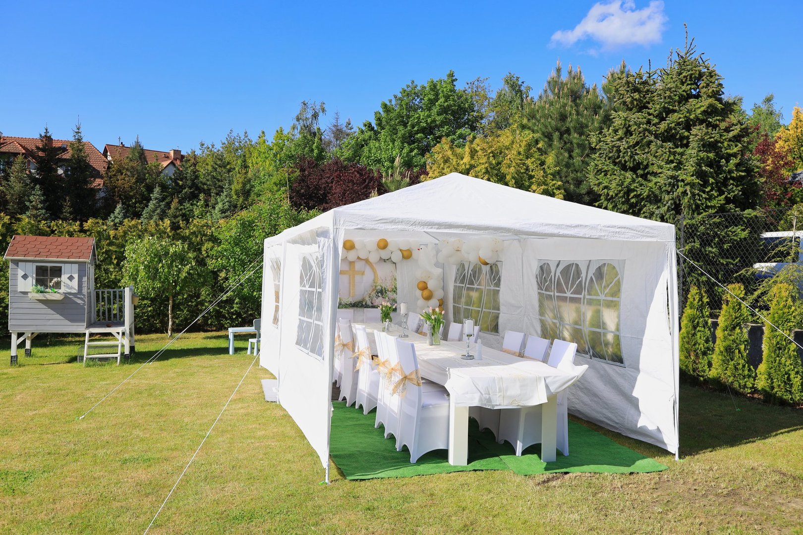 Garden tent for a communion party with a table and white decorations.