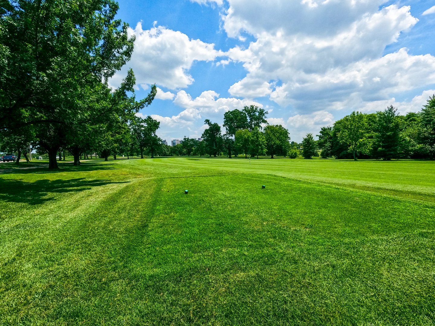 Beautiful open green space at a city park. Cloudy blue skies over trees and golf course fairway. Located at Forest Park in St. Louis, Missouri, USA.