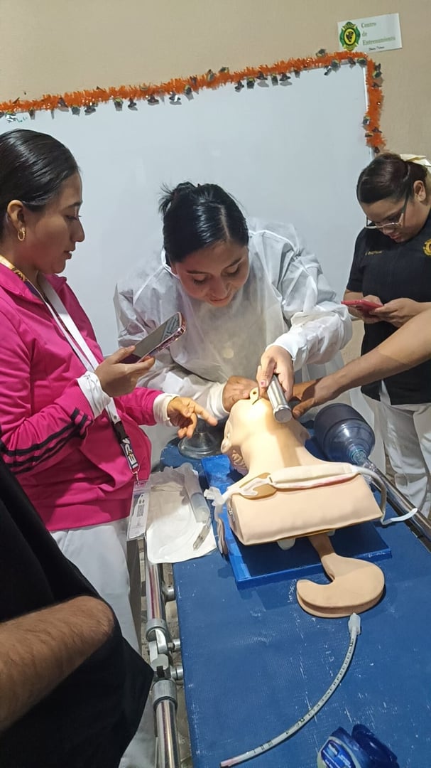 Medical students practice intubation on a mannequin, supervised by an instructor in a training setting.