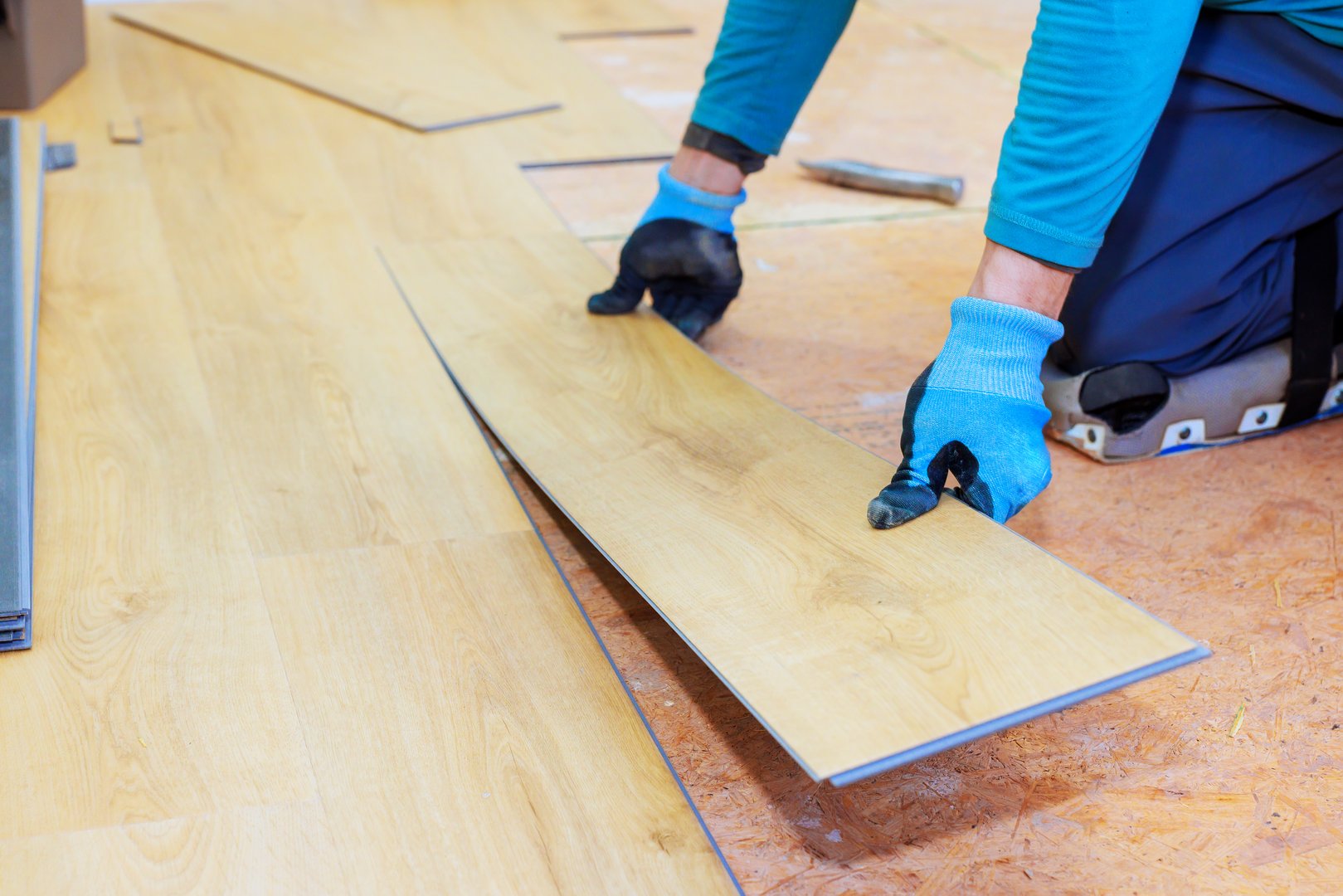 Worker installs planks of wooden flooring with care in residential space during room renovation