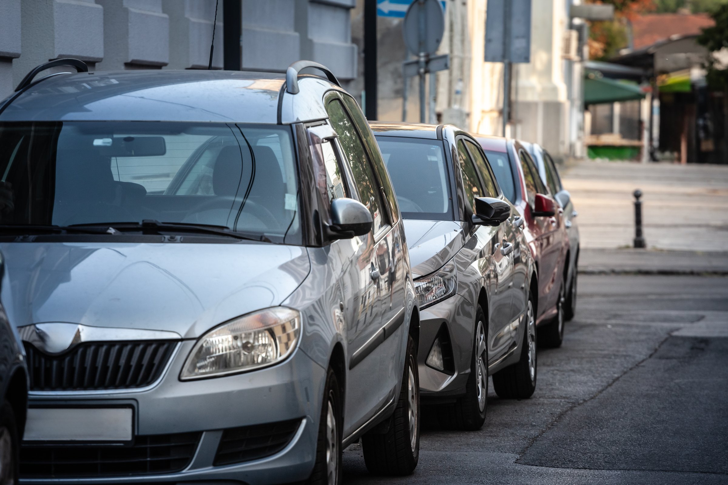 This editorial scene depicts a line of closely parked vehicles on a central Belgrade street in Serbia. Caught between historic architecture and modern demands, drivers maneuver limited space to stow their cars. The reflection of surrounding buildings on metal surfaces adds an urban character to the composition, underscoring the interplay of tradition and daily function. Commuters, pedestrians, and visitors alike share these bustling streets, where the ongoing challenges of congestion, infrastructure, and residential life reveal Belgrades evolving approach to city planning and transportation management.