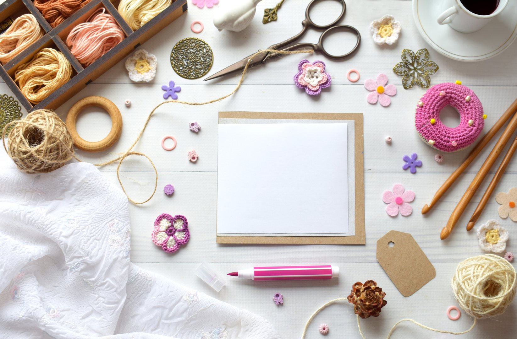 Creative flat lay composition of crafting supplies including threads scissors flowers buttons and a blank frame on white background perfect for DIY handmade decoration and sewing projects