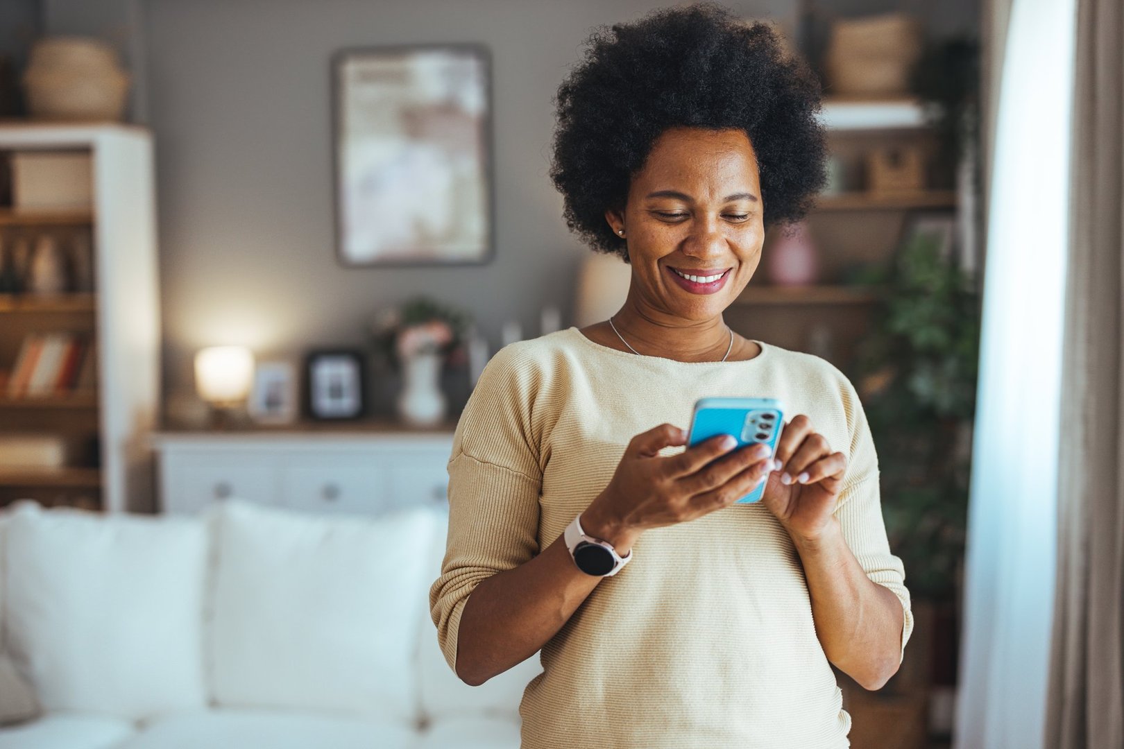 Happy woman using smartphone at home