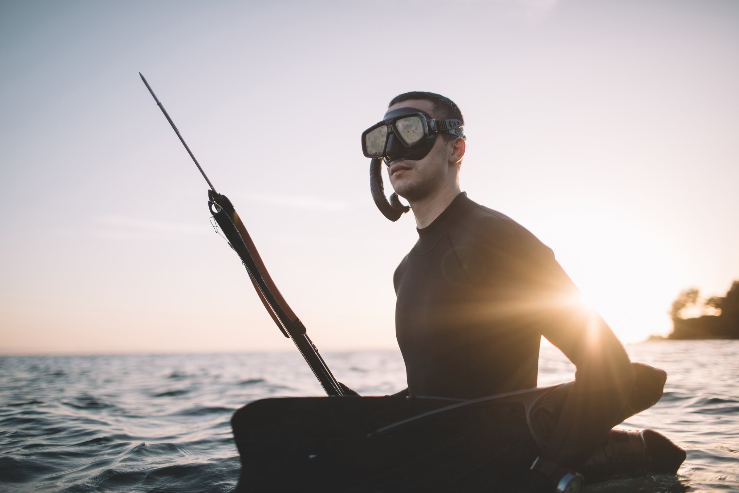 Young active man in wetsuit ready for spearfishing.