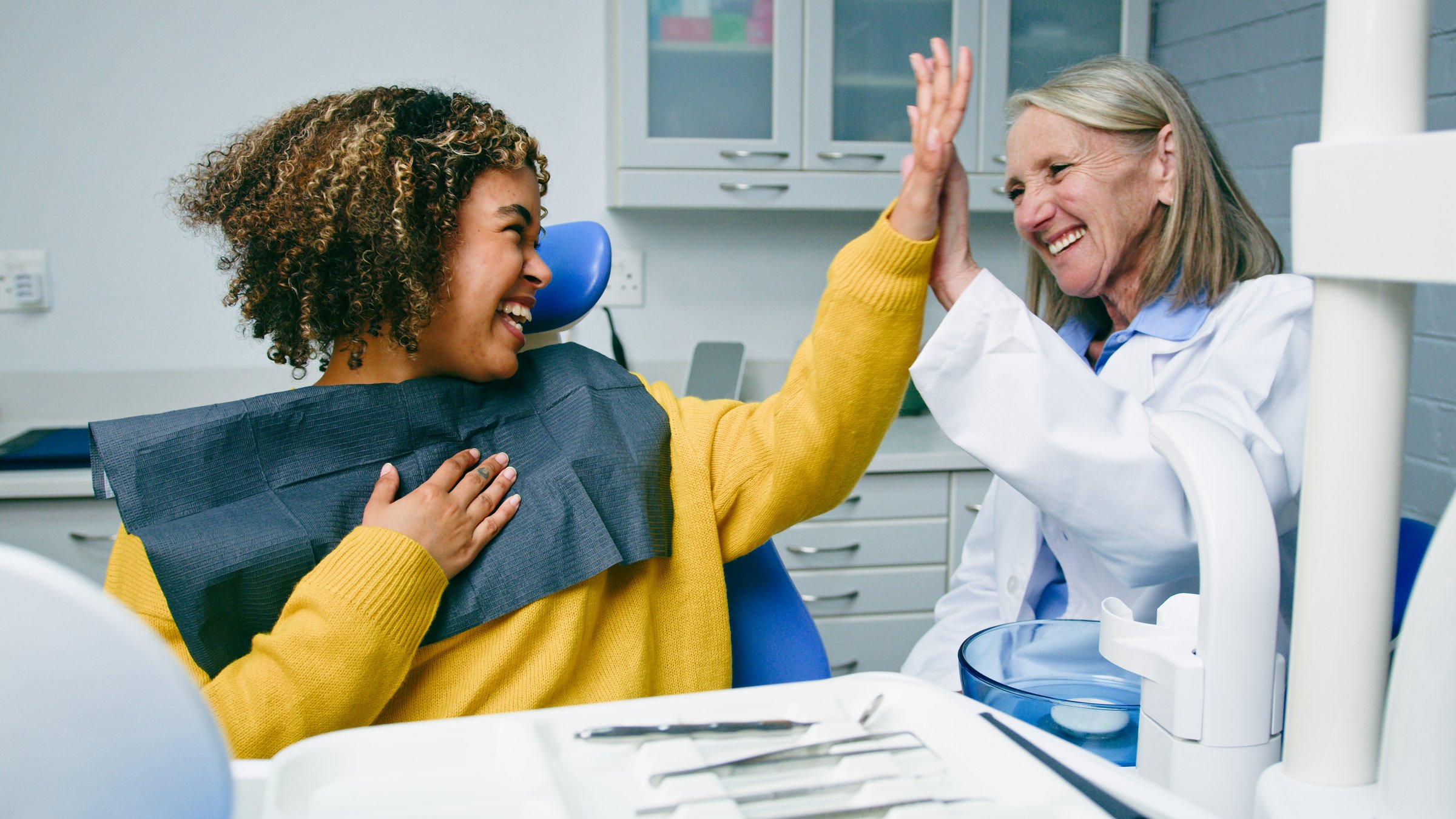 A cheerful interaction between a patient and a dentist, sharing a high-five after a successful appointment. The image conveys satisfaction, trust, and professionalism in a clean and modern dental office environment.