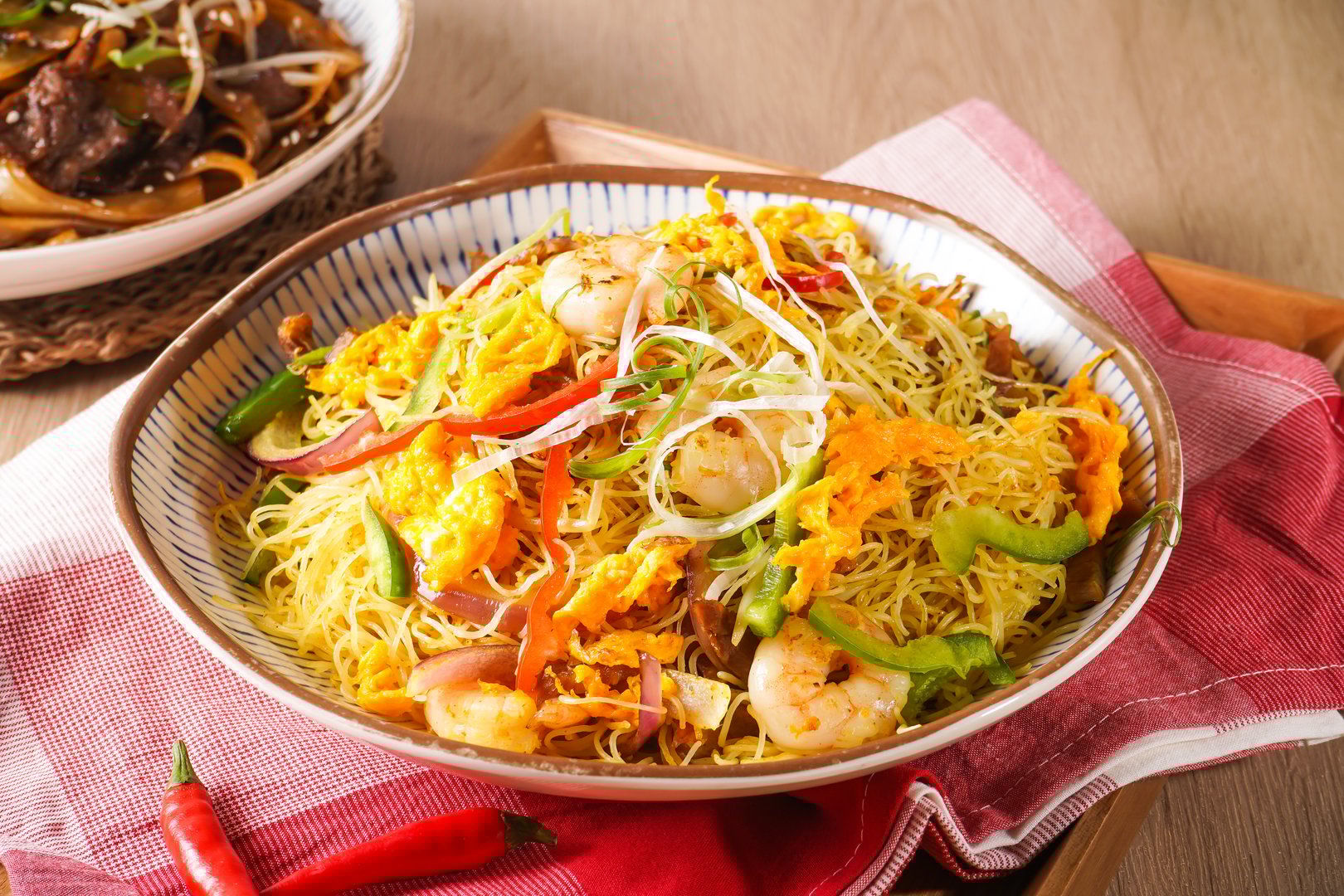 Xing zhou Fried Rice or Singapore Style Fried Rice including shrimp, vegetables, and egg served in pot isolated on napkin side view of hong kong food on wooden background