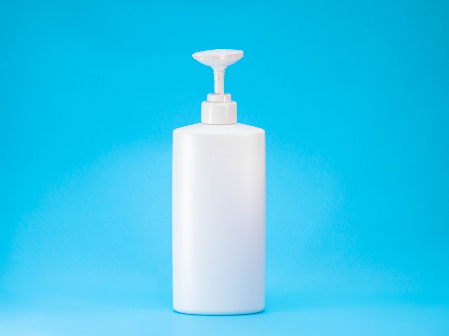 Minimalist white plastic pump bottle on a bright blue background. Suitable for mockups or product presentations related to cosmetics, skincare, soap, shampoo or hand sanitizer.