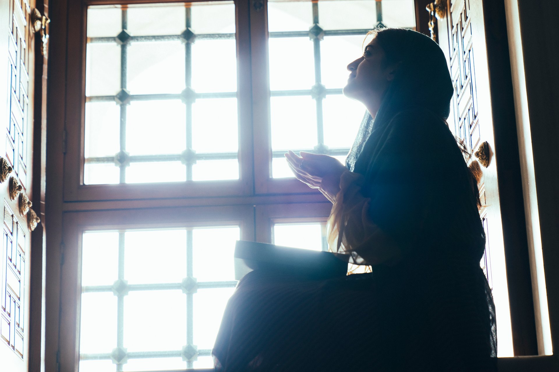 Muslim woman in headscarf and hijab prays with her hands up in air in mosque.Religion praying concept.