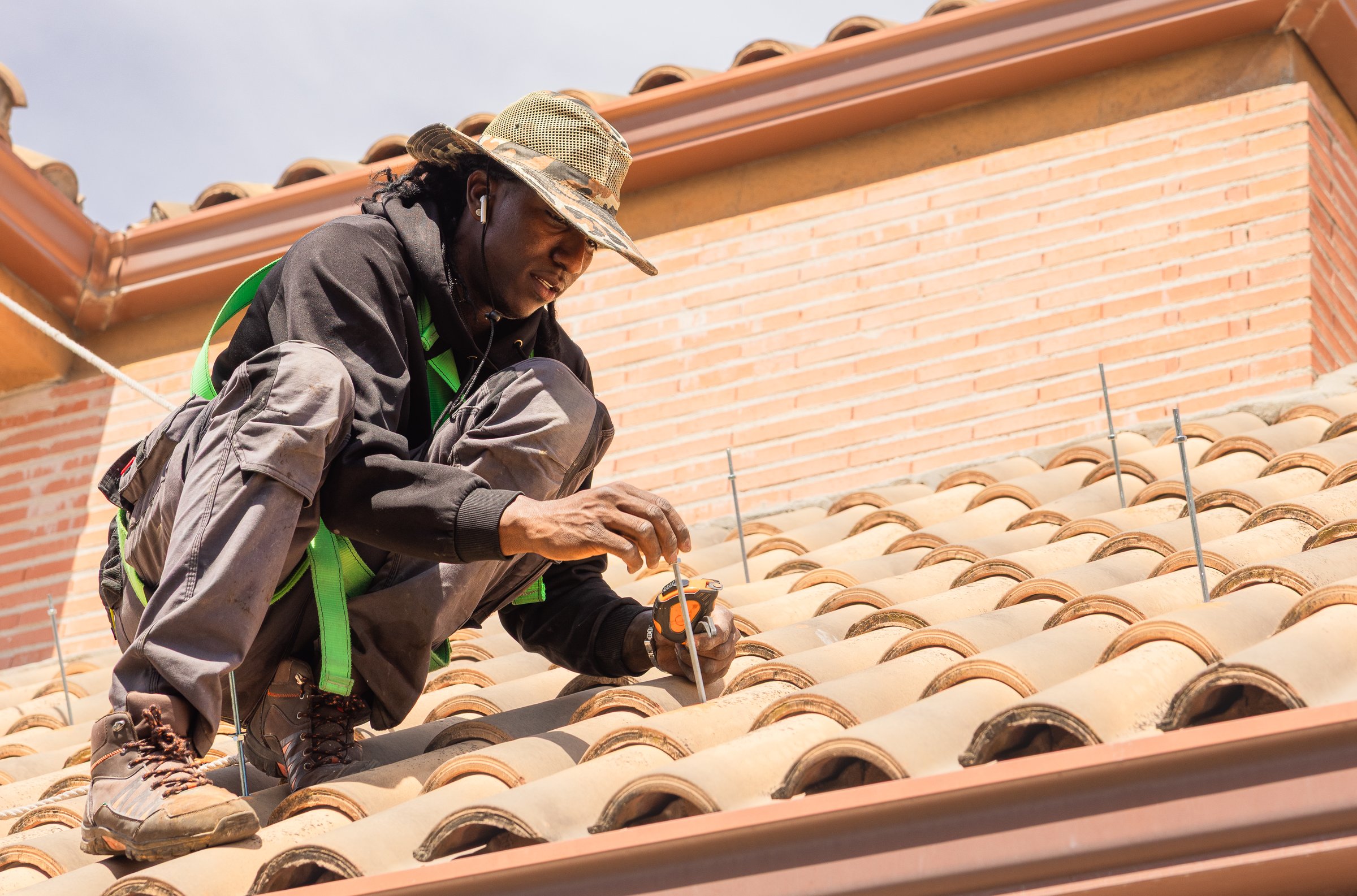 Young african american worker installing photovoltaic solar panels on a roof