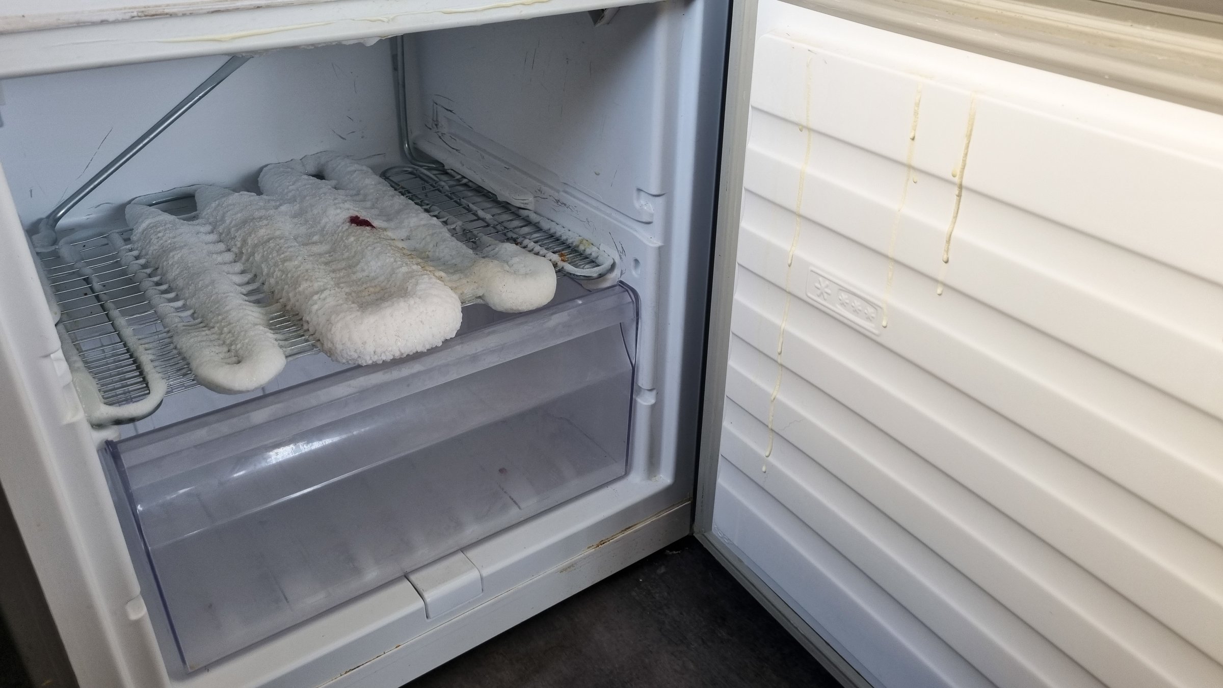 Empty and dirty open freezer in need of deep cleaning