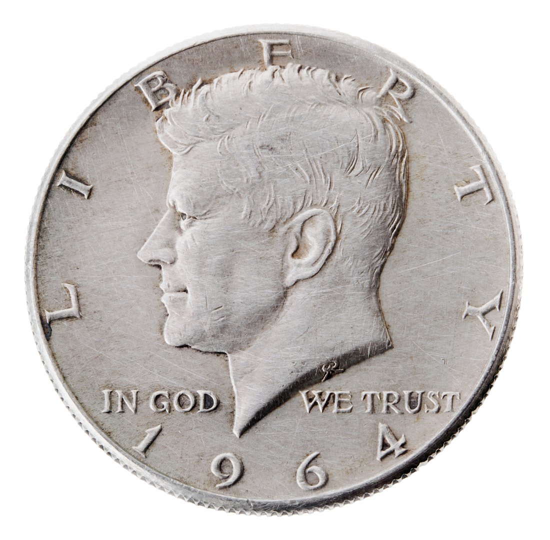 Frontal view of the obverse (heads) side of a silver half Dollar minted in 1964. Depicted is a profile portrait of John F. Kennedy and comes to honor his memory.