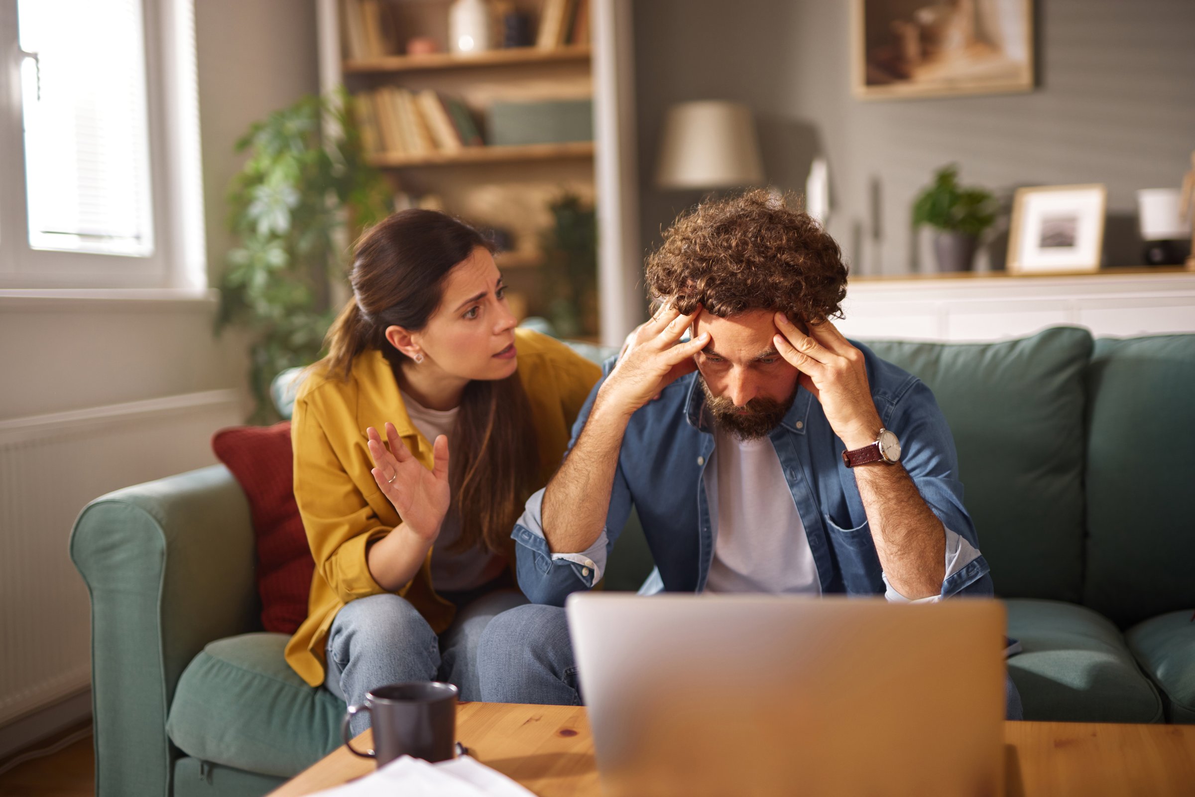 Worried couple arguing about their financial problems while looking at their laptop at home