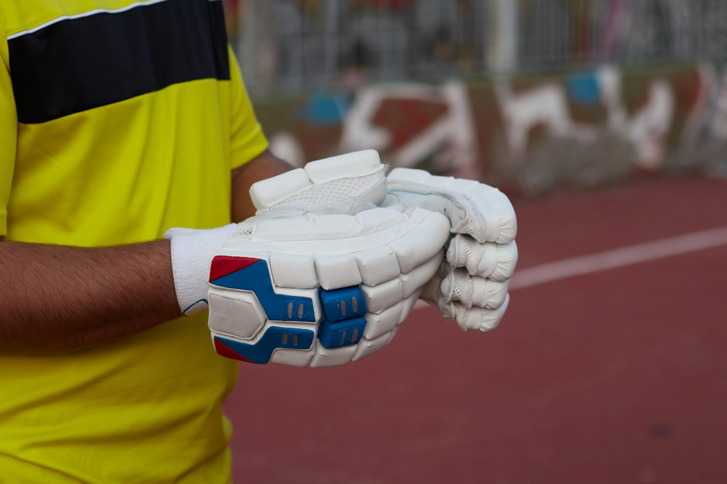 Young cricket player with white gloves and yellow uniform