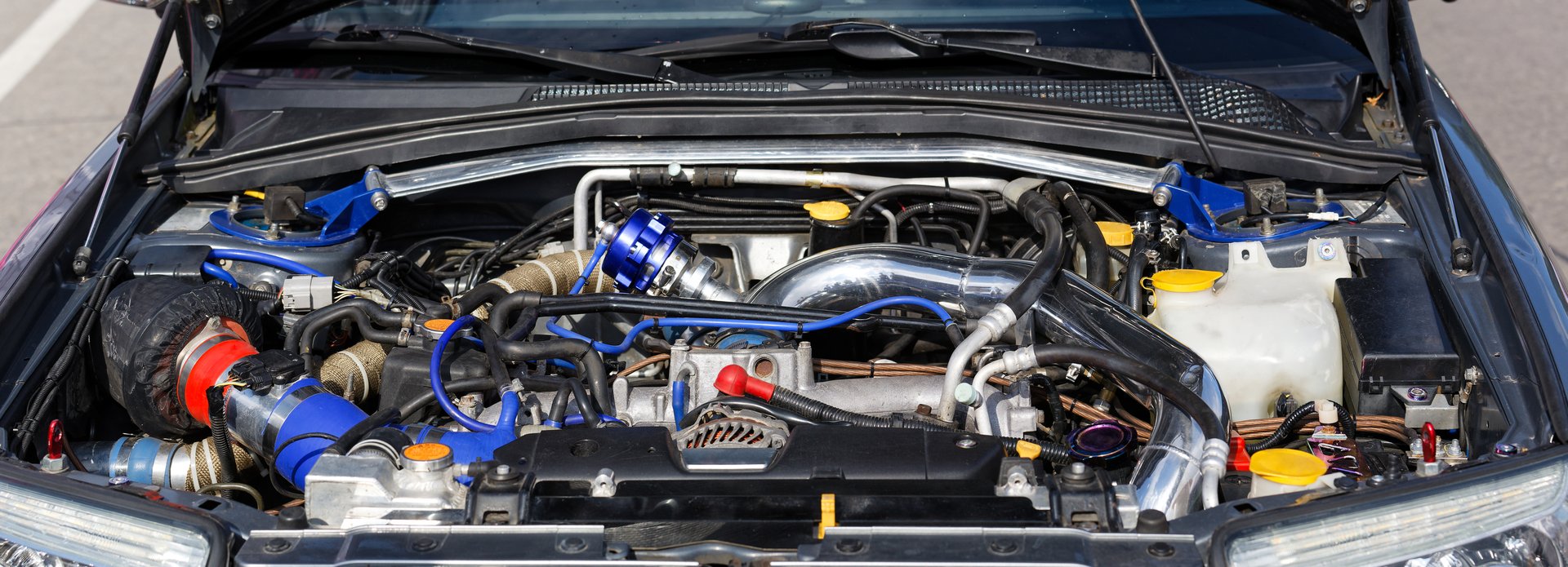 Close up detail of forced engine with turbocharged under the open hood of car. Front view.