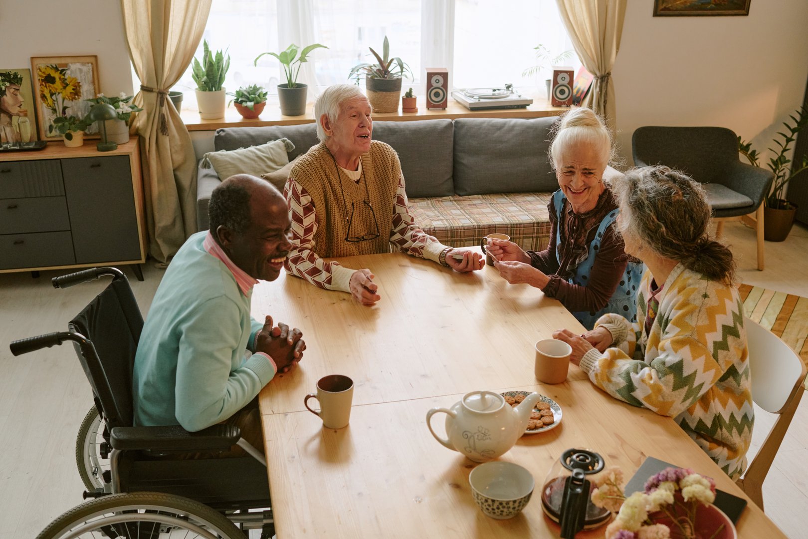 High angle shot of biracial company of elderly friends sitting at table chatting and enjoying tea time