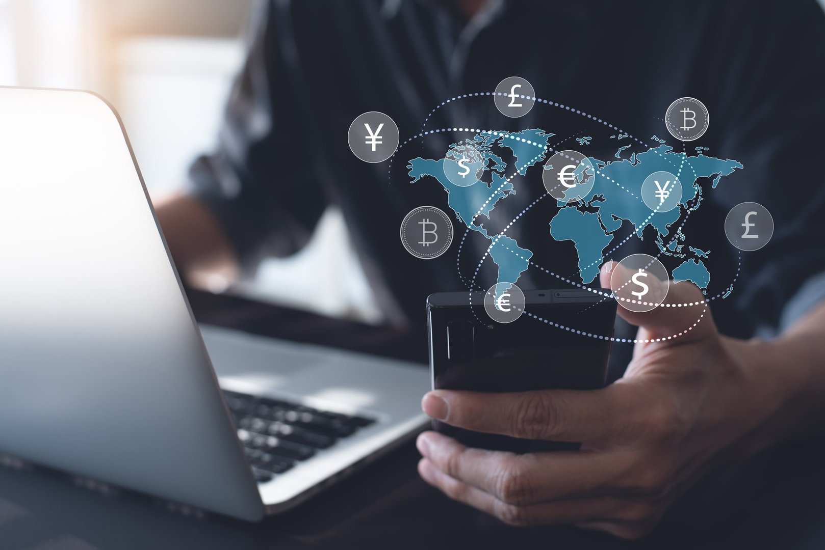 Currency exchange, money transfer, FinTech financial technology, Global business, online banking, interbank payment concept. Man using mobile phone and laptop computer with international currencies and world map on virtual screen