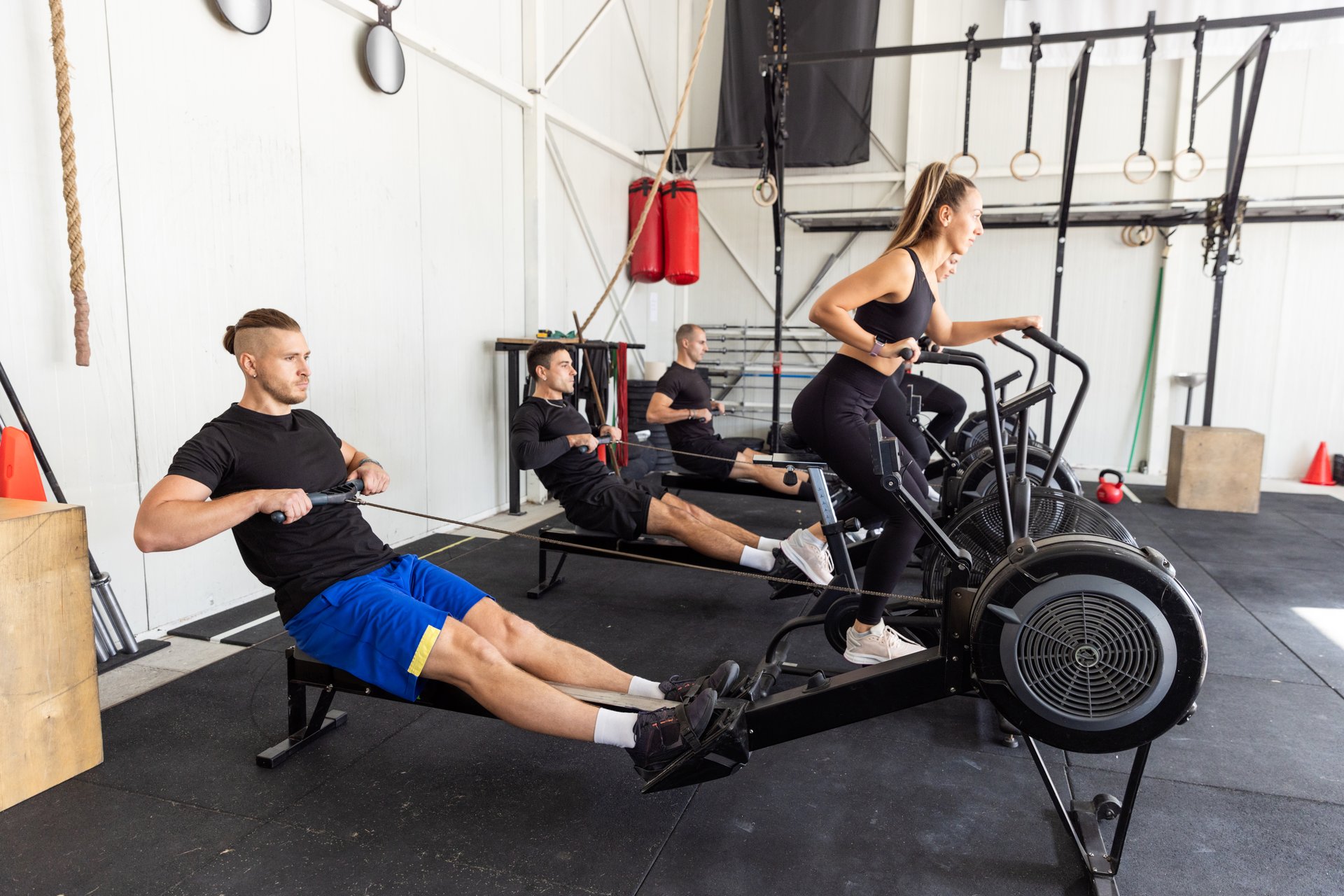 Fitness group having high Intensive workout on a bike and on a rowing machine in the industrial gym