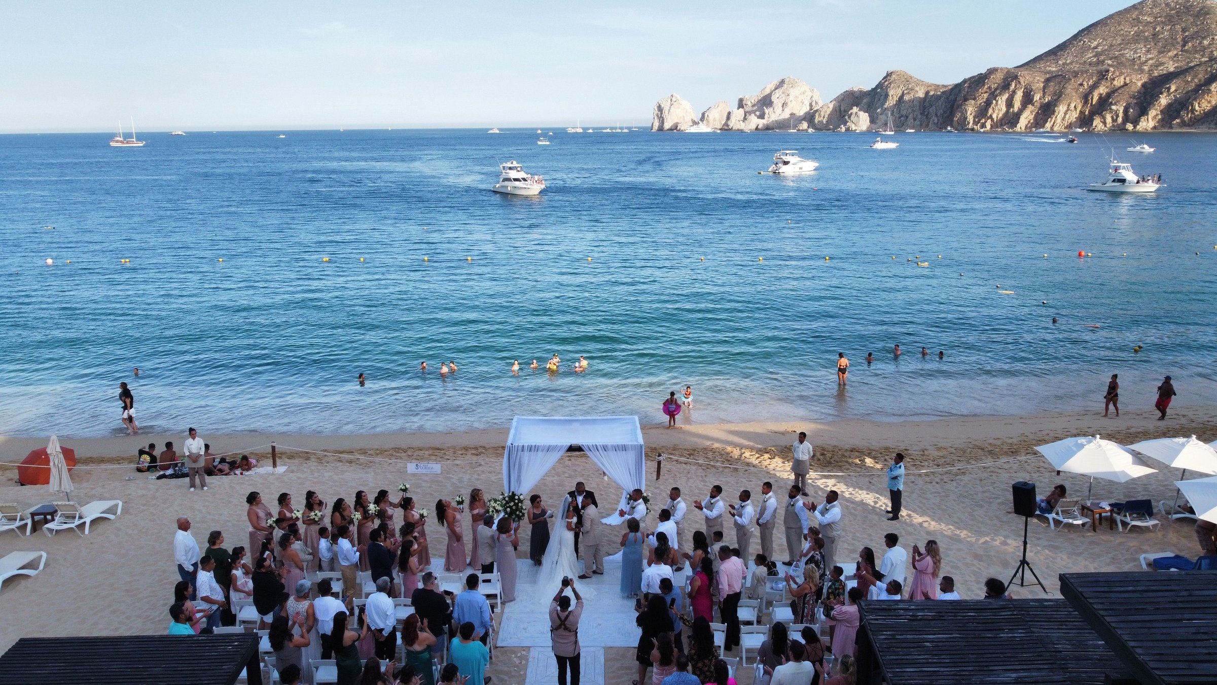 Los Cabos, Mexico – November 24, 2024: A wedding celebration on a beach with people gathered under a sunny sky