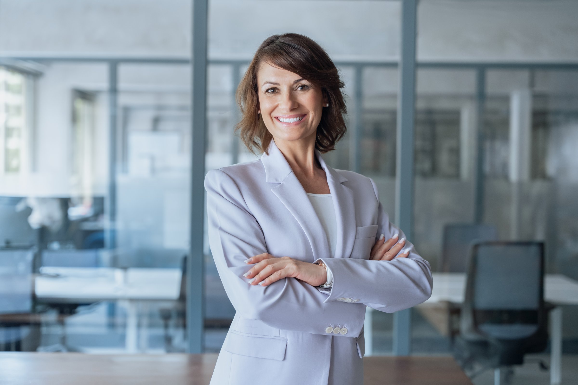 40s latin hispanic senior business mentor coach woman leader with crossed arms smiling at camera. European confident mature middle aged leader female businesswoman manager standing in office workspace