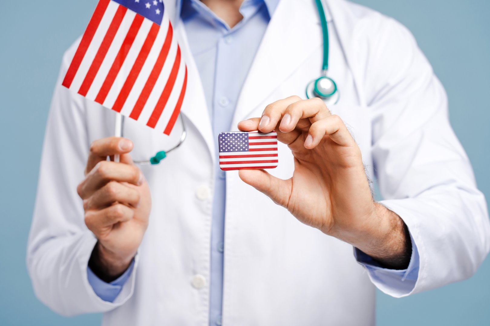 Doctor holding, showing USA flag, selective focus on hand. Patriot, freedom concept