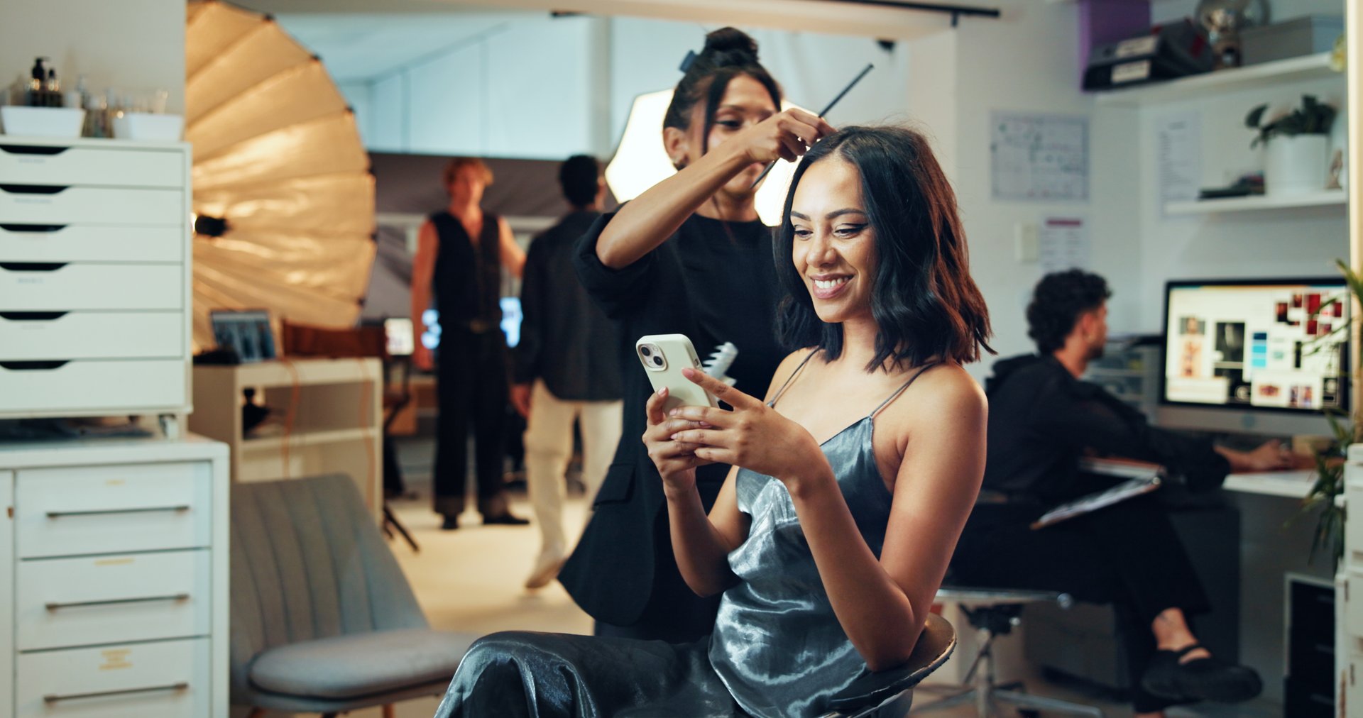 Makeup, phone or photography with hair stylist and model in studio for behind the scenes preparation.