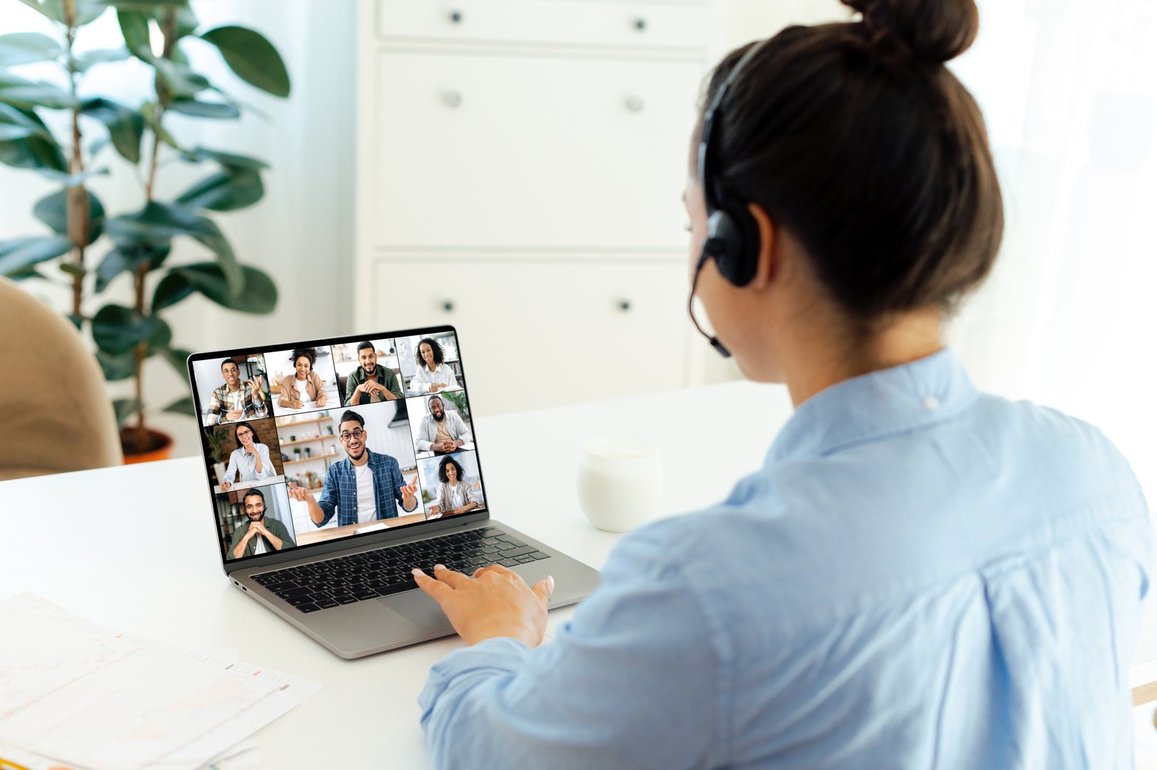 Virtual meeting by video conference. Successful caucasian business woman sits at a workplace, uses laptop, having negotiating use video call, multiracial business people on a computer screen