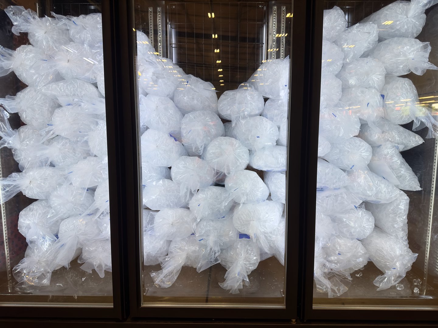 Individual packs of cubed ice selling in a supermarket vertical freezer