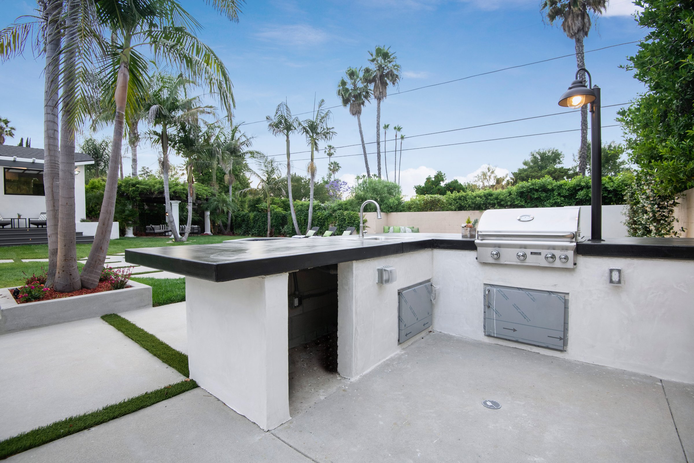 An outdoor kitchen with palm trees backdrop in a modern new construction home in Los Angeles