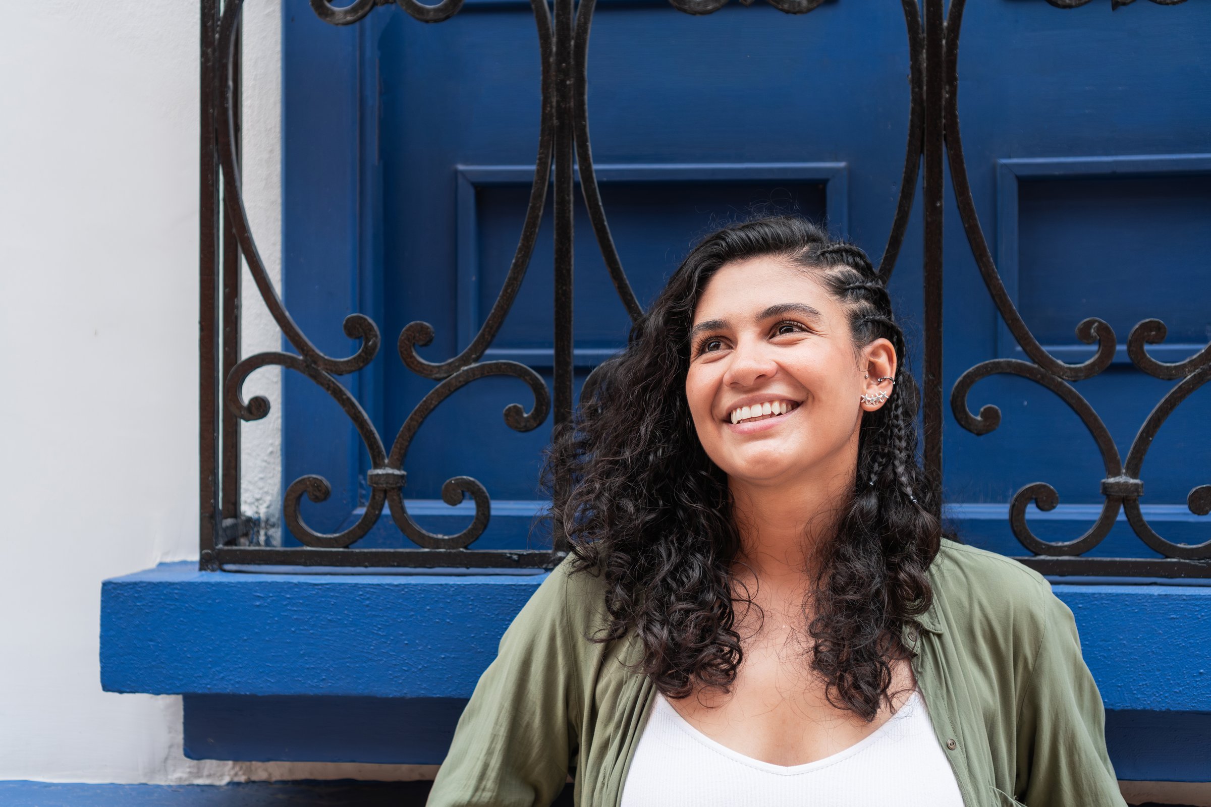 Smiling Latina woman standing outdoors against a blue door