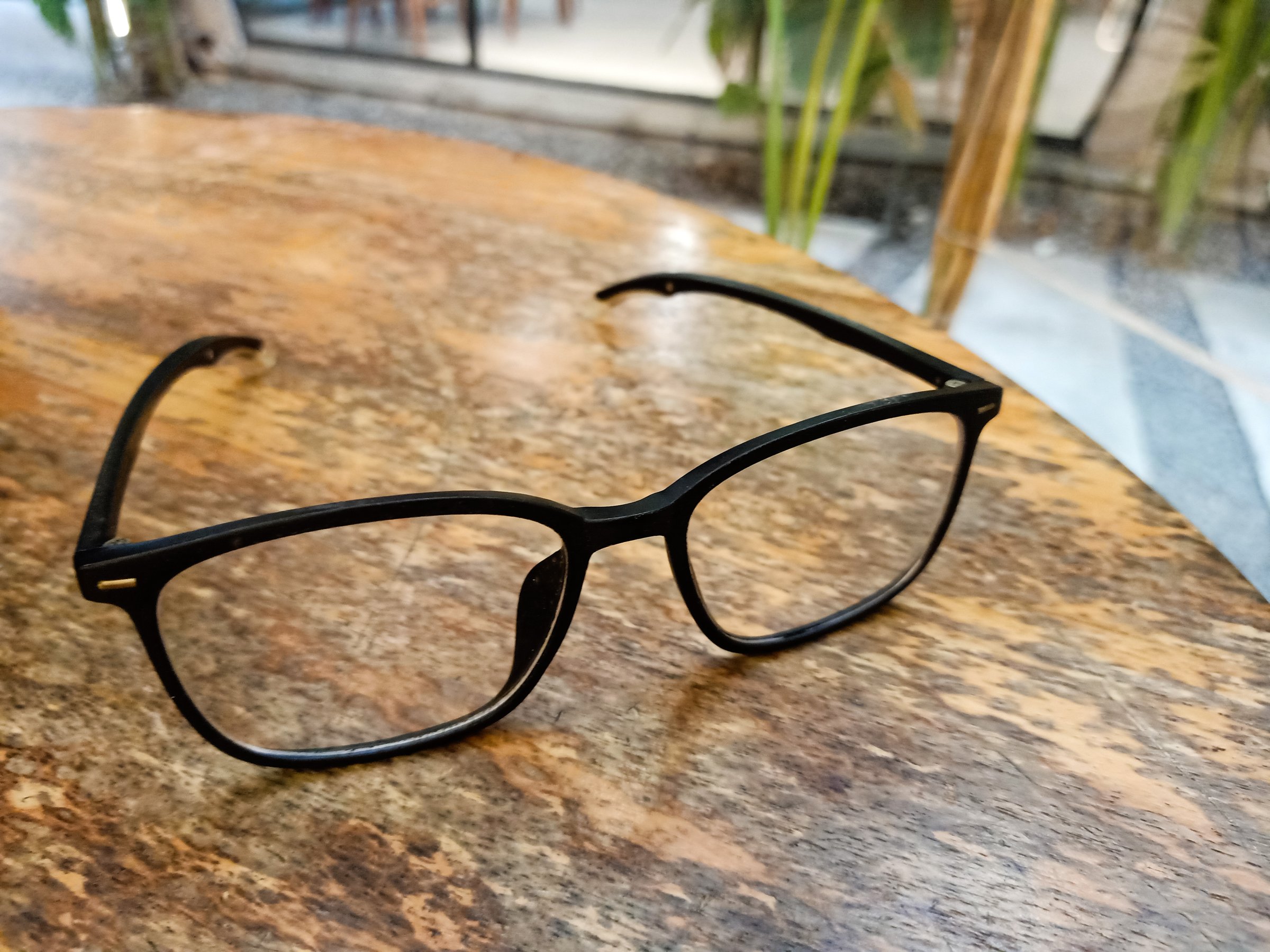 black frames glasses facing right side on wooden table