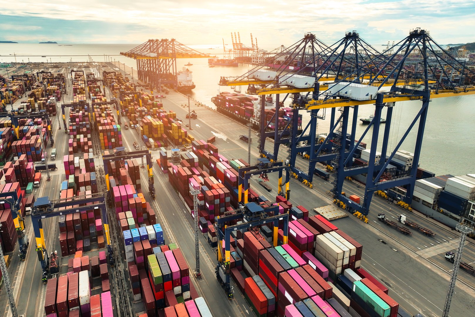 Container ship docked at port with cargo trucks and cranes. Global logistics hub. Maritime freight operations. International trade and supply chain management. Import-export terminal. Global commerce.