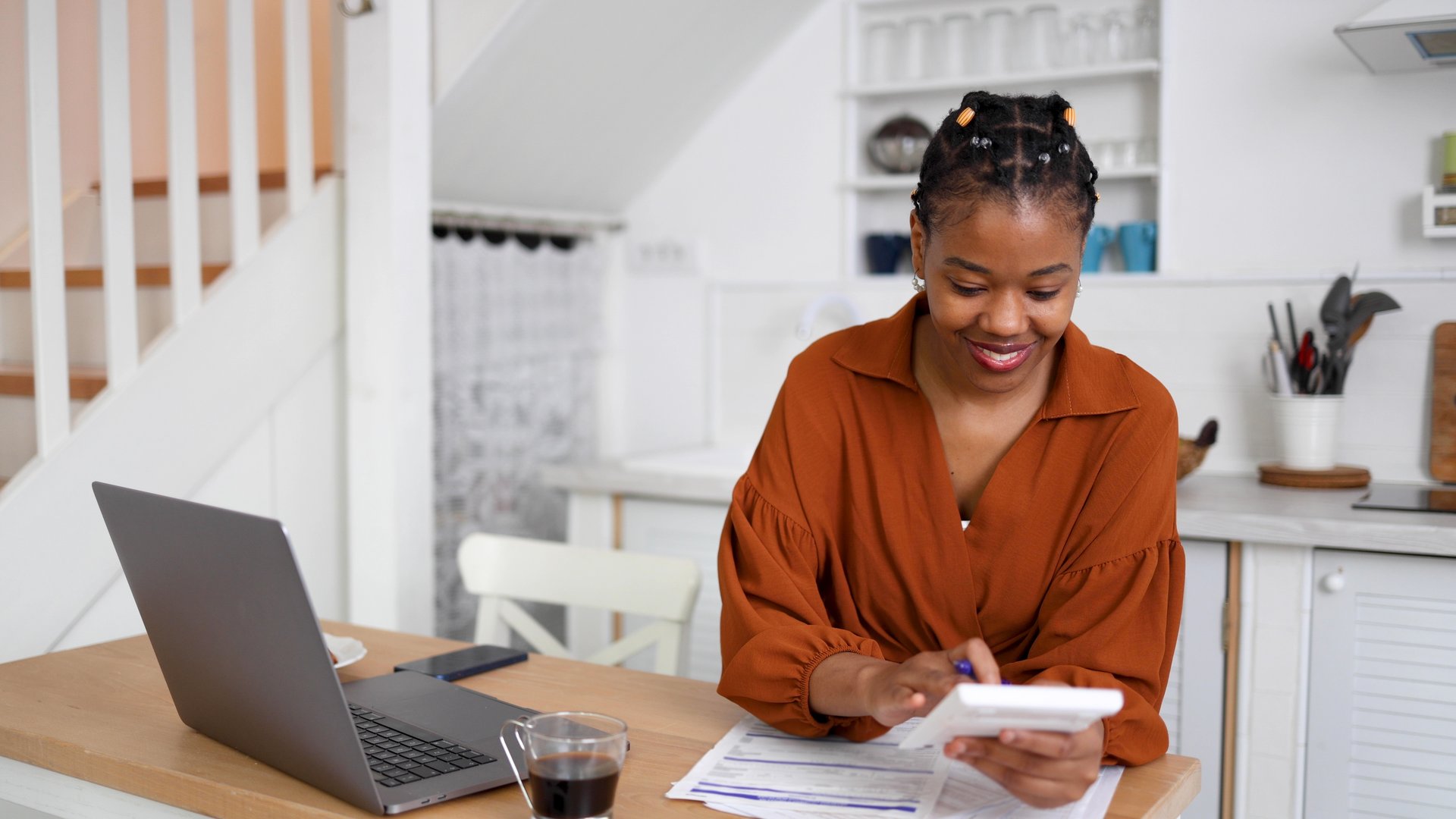 African American young woman enjoying coffee and managing her finances at home