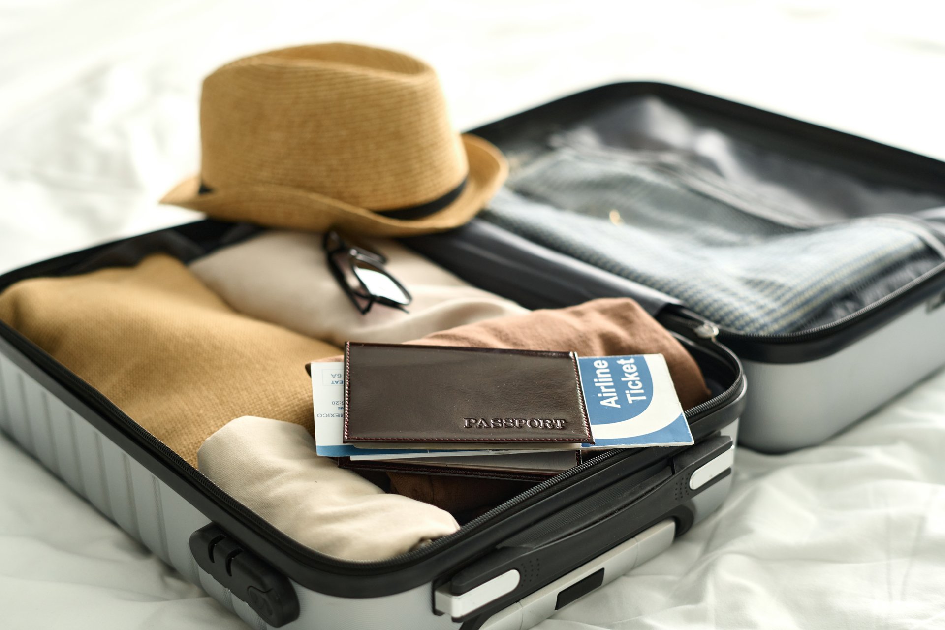 Background image of open suitcase with passport and airplane ticket on bed in hotel room travel concept