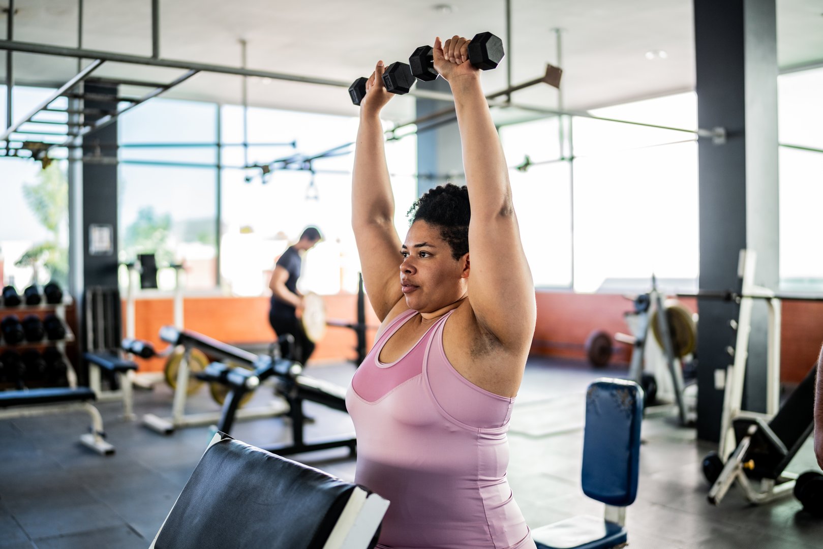 Mid adult woman doing shoulder exercise with dumbbell at gym