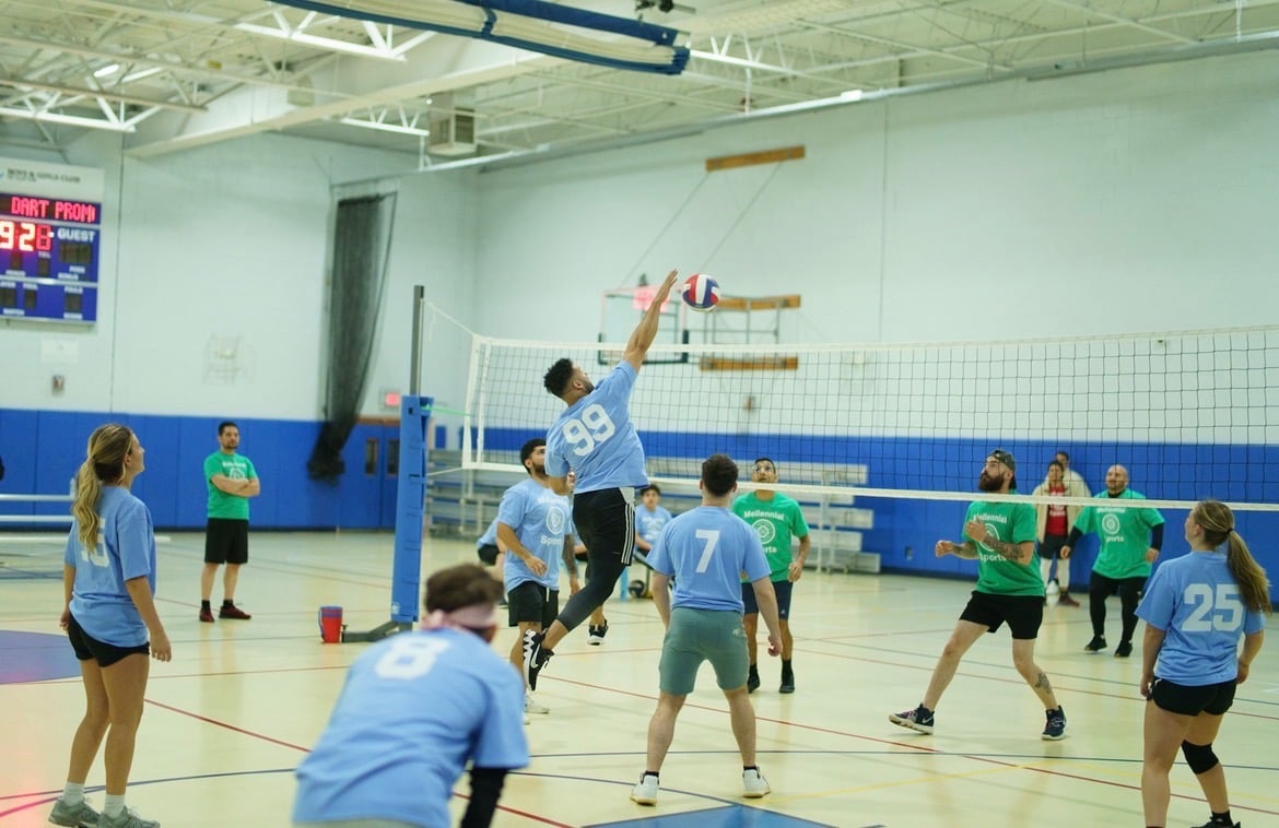 Group of friends playing volleyball together on beach