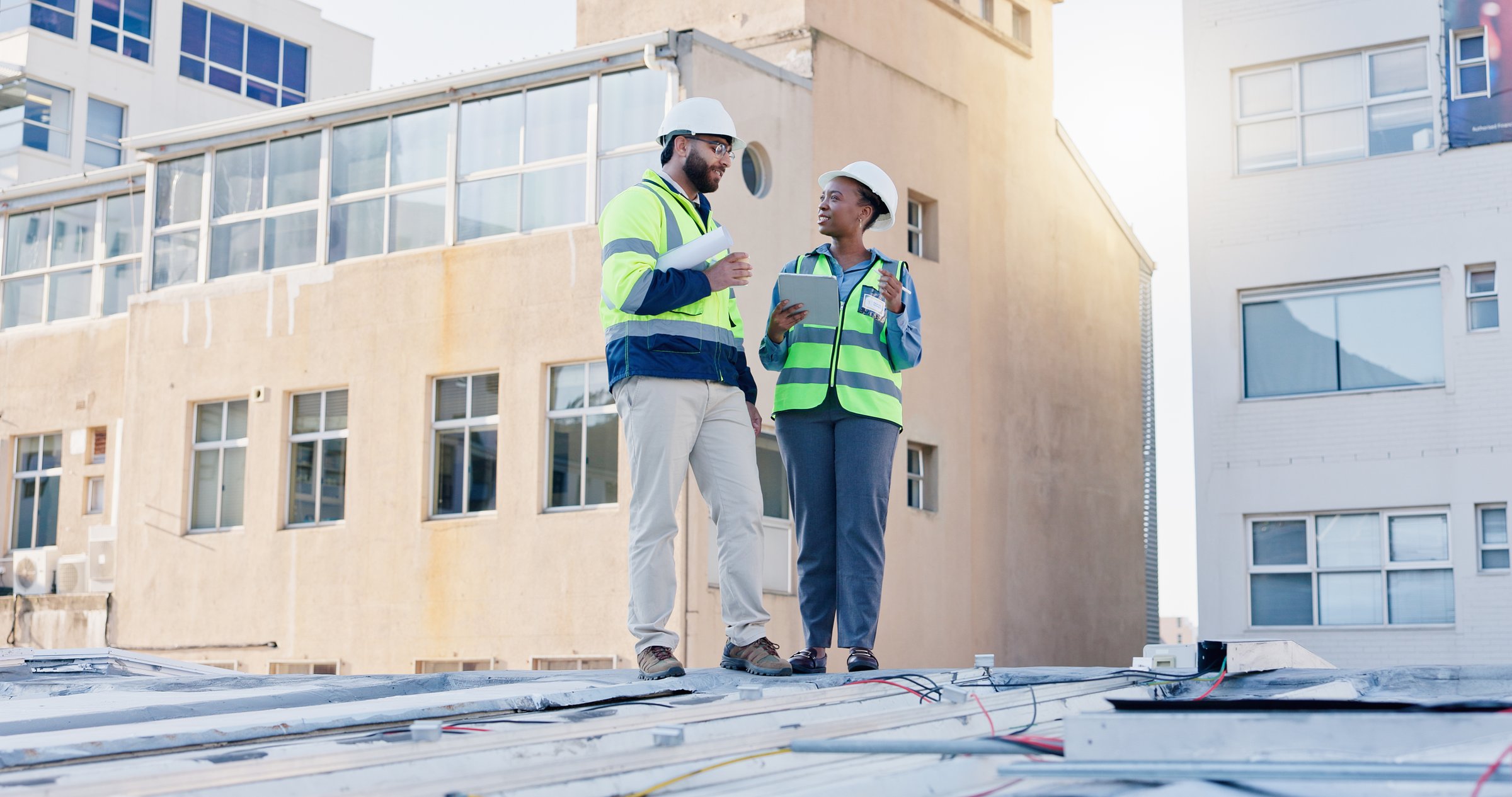 Business people, technician and discussion with tablet on rooftop for building maintenance or installation in city. Contractor, electrical engineer or electricians with technology for roof inspection