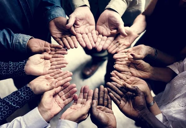 Diverse group of people's hands open in a circle, showcasing unity and diversity.