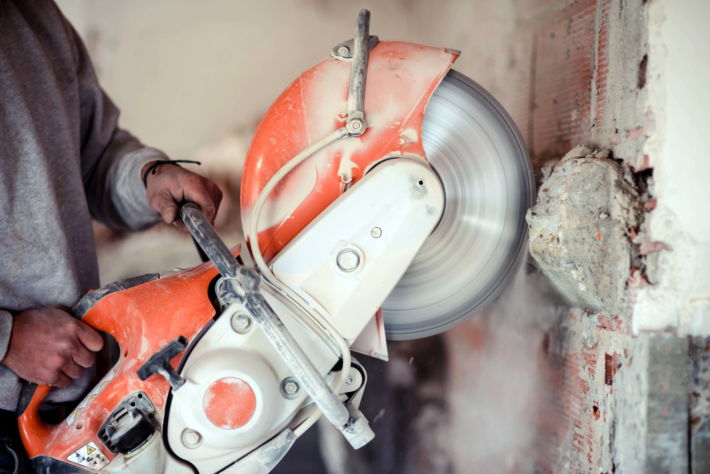 Worker cutting a concrete wall inside a house