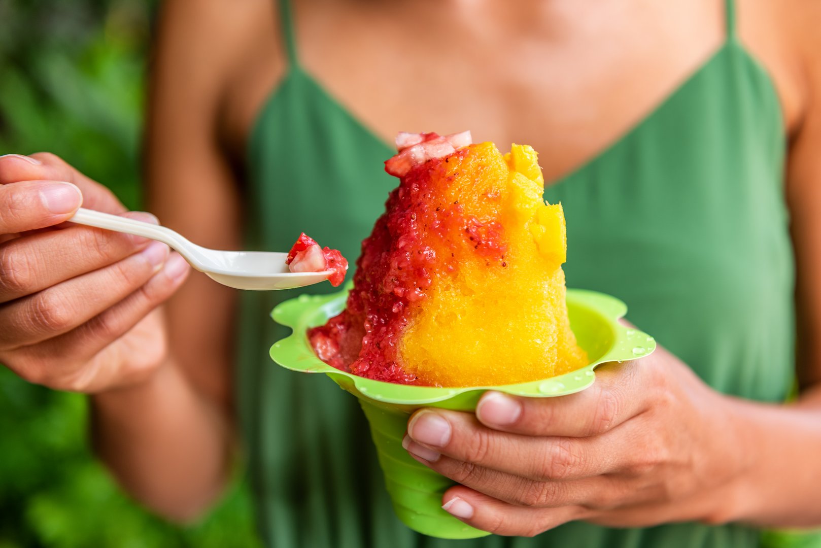 Shave Ice Hawaii local food woman eating hawaiian shaved ice cream treat in Honolulu Waikiki beach, Hawaii, USA.