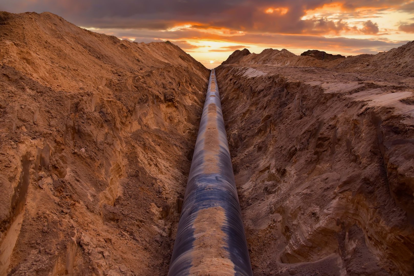 Pipeline Construction. Natural Gas Pipeline trench in ground on sunset. LNG, LPG. Oil and Gas Transportation crude oil, natural gas. Crude pipeline. Pipework. Pipes for Petrochemical industry.