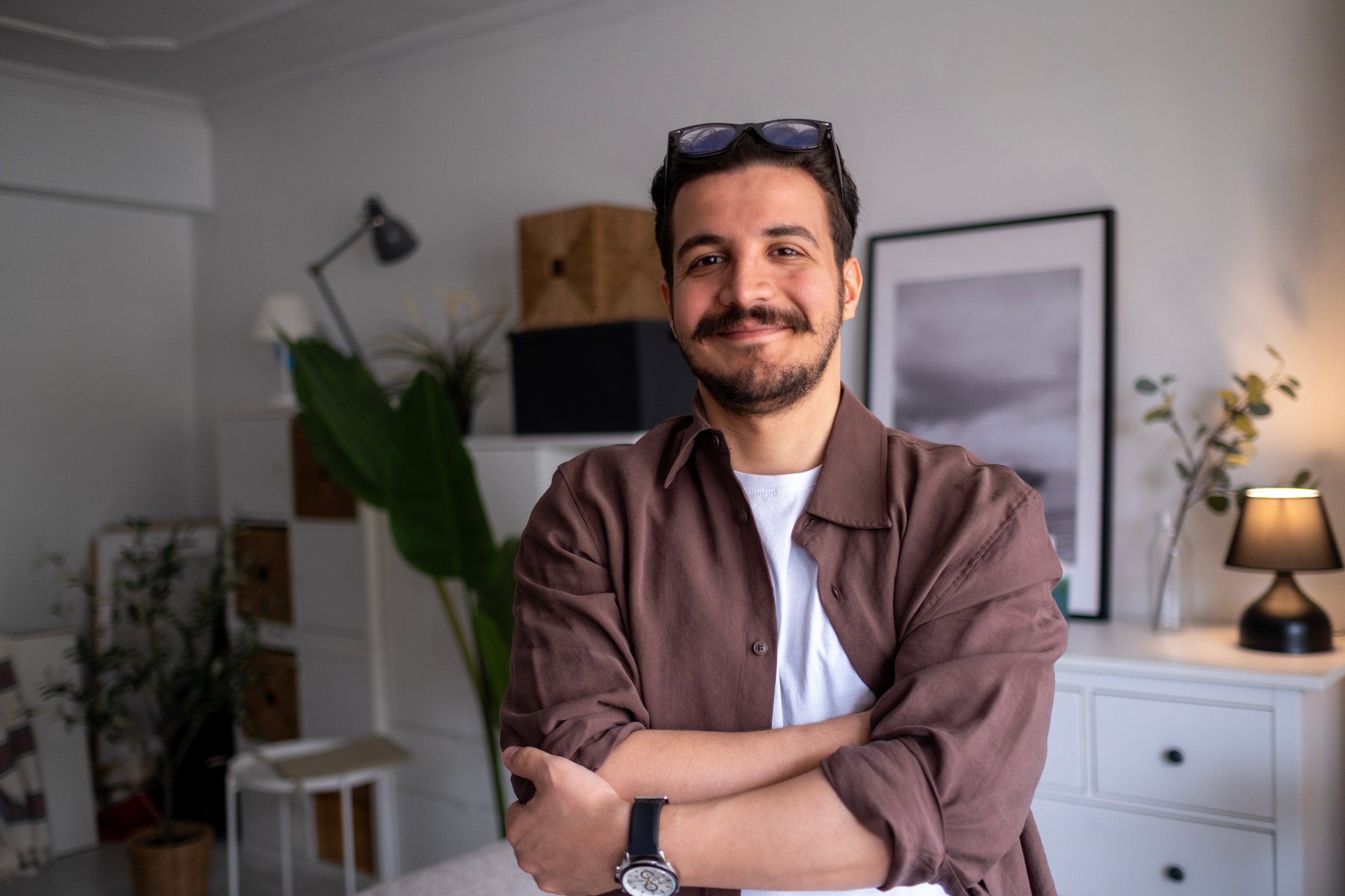 Portrait of handsome confident smiling businessman standing in the office and looking at camera.Head shot portrait of smiling businessman with arms crossed