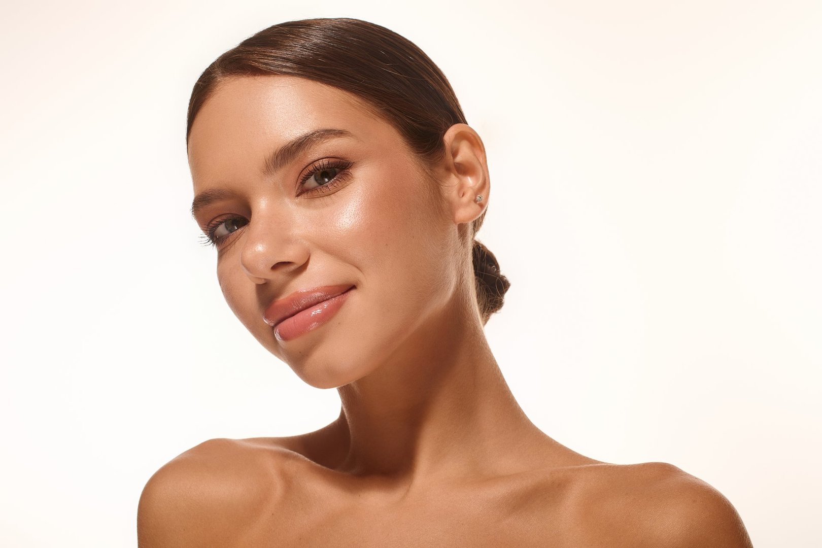 A young woman showcases her natural beauty and soft smile on a bright white backdrop.